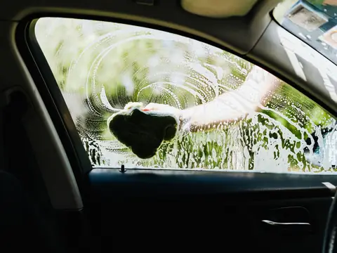 A driver's side window being cleaned, seen from inside the car